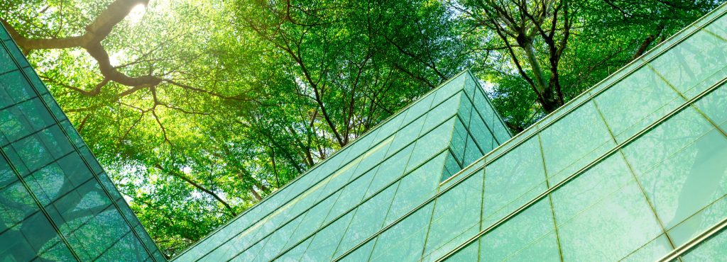 Eco-friendly building in modern city. Sustainable glass office building with trees for reducing carbon dioxide. Office building with green environment. Corporate building reduce CO2. Net zero emission